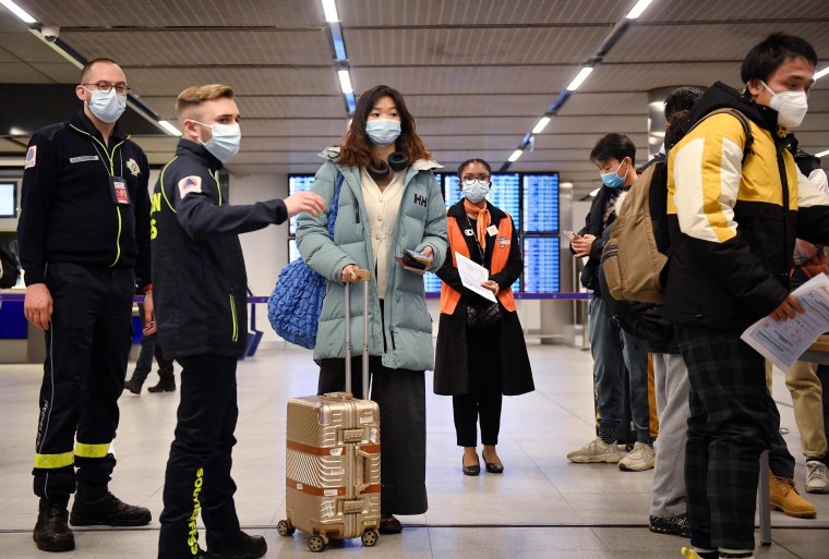 Travellers arriving from China wait in a line to have their COVID-19 vaccination documents checked after arriving at the Paris-Charles-de-Gaulle airport in Paris