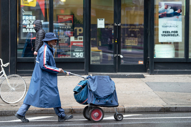 A U.S.P.S mailman wearing a rain coat and hat walks on a quiet street amid the coronavirus pandemic on April 24, 2020 in New York City, United States. COVID-19 has spread to most countries around the world, claiming over 196,000 lives with over 2.8 million cases.