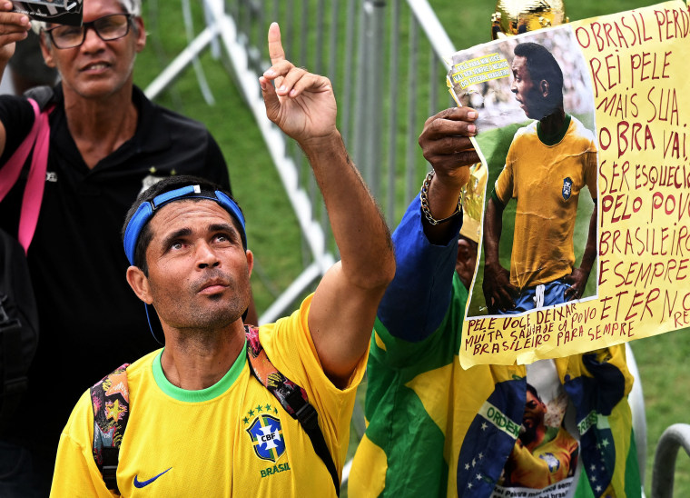Un fanático de la leyenda del fútbol brasileño Pelé hace un gesto mientras asistía a su llamada de atención en el estadio Urbano Caldeira en Santos, Sao Paulo, Brasil. 
