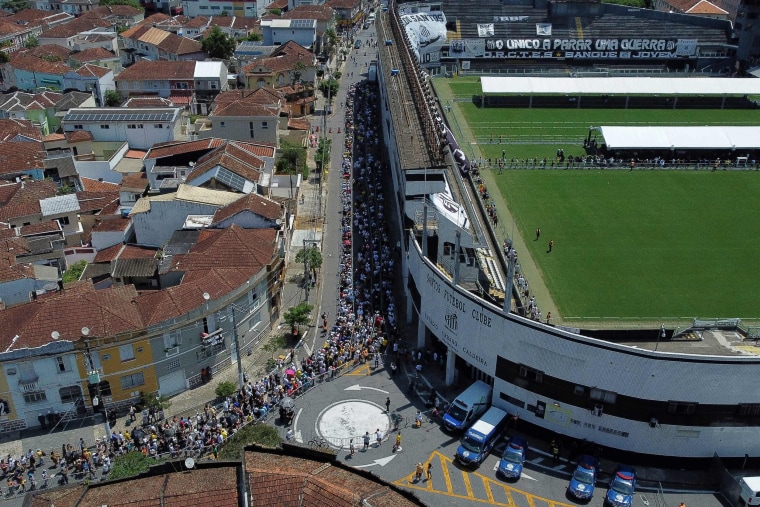 Los fanáticos de la leyenda del fútbol brasileño Pelé se reúnen afuera del estadio Urbano Caldeira para ver su velorio en Santos, Sao Paulo, Brasil. 