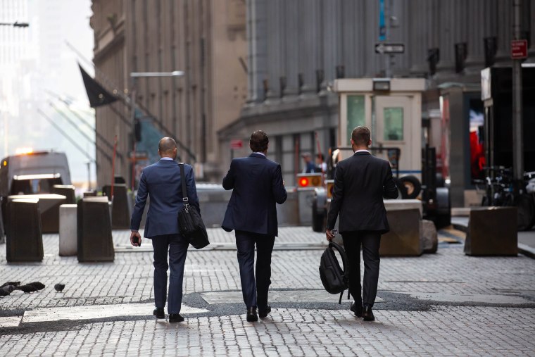 Pedestrians walk along Wall Street  in New York