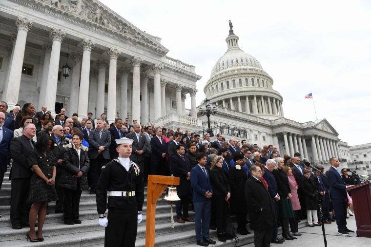 A bipartisan group of lawmakers observe a moment of silence on the steps of the Capitol