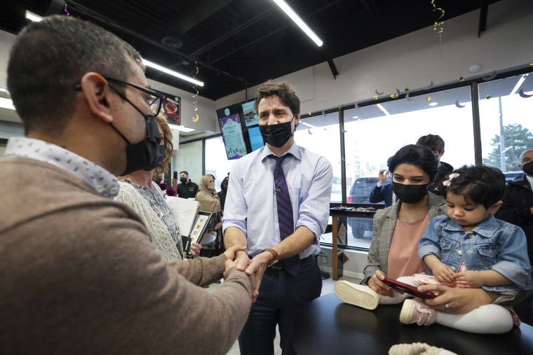 Canadian Prime Minister Justin Trudeau, center, shakes hands with Ahmad Najib Wahidi, left, and his daughter, 14-month-old Harir Wahidi, right, and mother Marghana Elyaskhil, center, as he meets with families who have resettled from Afghanistan at the Eastern Food Market in Hamilton, Ontario, on May 6, 2022.