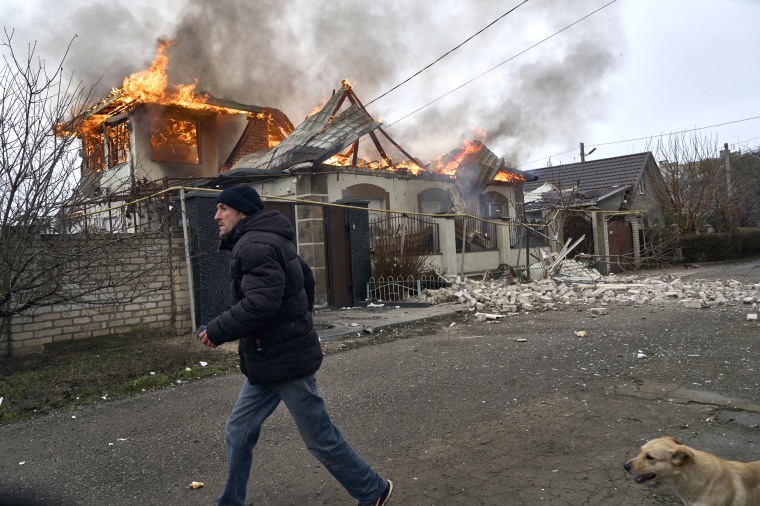 A local resident runs past a burning house hit by the Russian shelling in Kherson, Ukraine