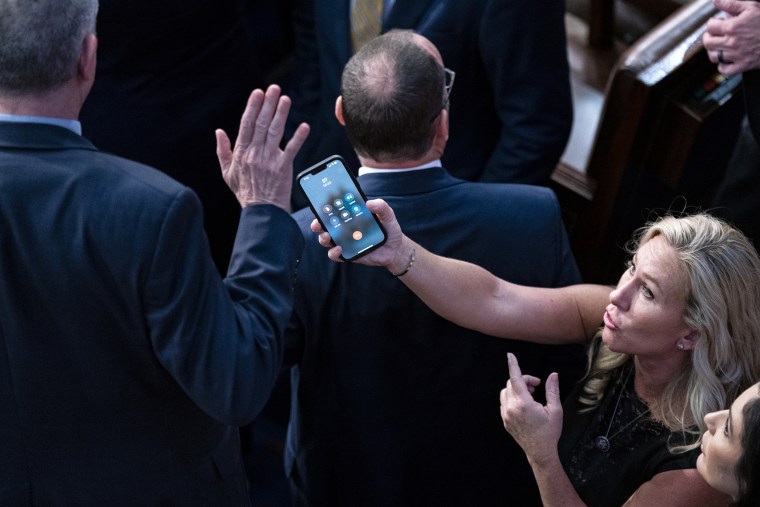 Representative Marjorie Taylor Greene, a Republican from Georgia, holds her smart phone with former US President Donald Trump on the line, as Representative Matt Rosendale, a Republican from Montana, waves it off during a meeting of the 118th Congress in the House Chamber at the US Capitol in Washington, DC, US, on Friday, Jan. 6, 2023. McCarthy was increasingly confident that he'll gain the additional votes he needs to be elected as House speaker after converting some of the holdouts that had blocked him over the previous three days. Photographer: Al Drago/Bloomberg via Getty Images