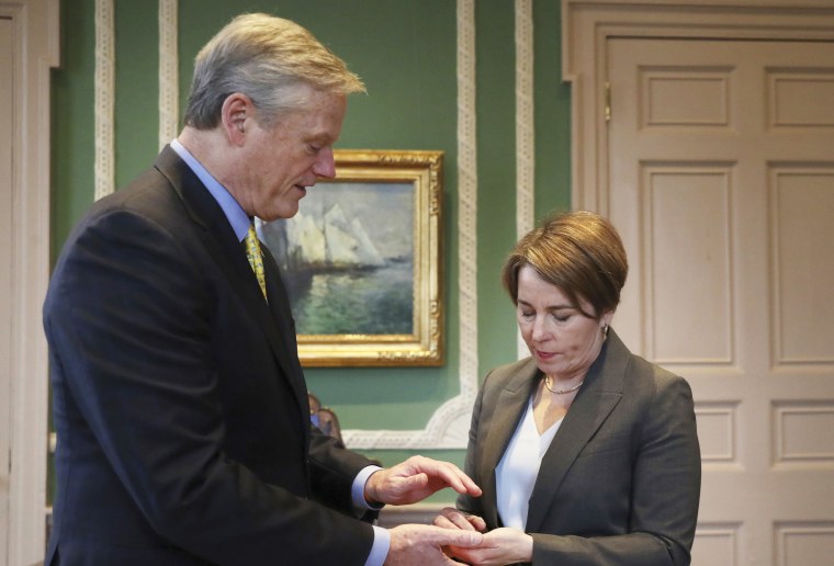 Former Gov. Charlie Baker and Gov. Maura Healey participate during a ritual exchange at the State House