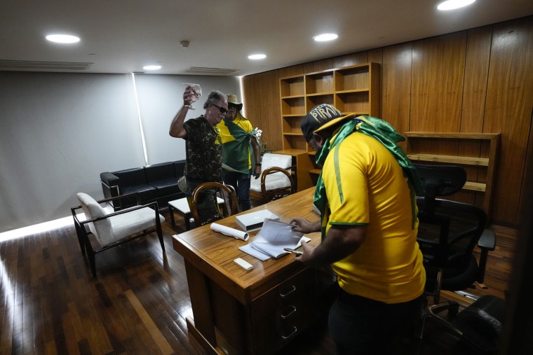 Supporters of Brazil's former President Jair Bolsonaro rifle through papers on a desk after storming the Planalto Palace in Brasilia on Jan. 8, 2023.