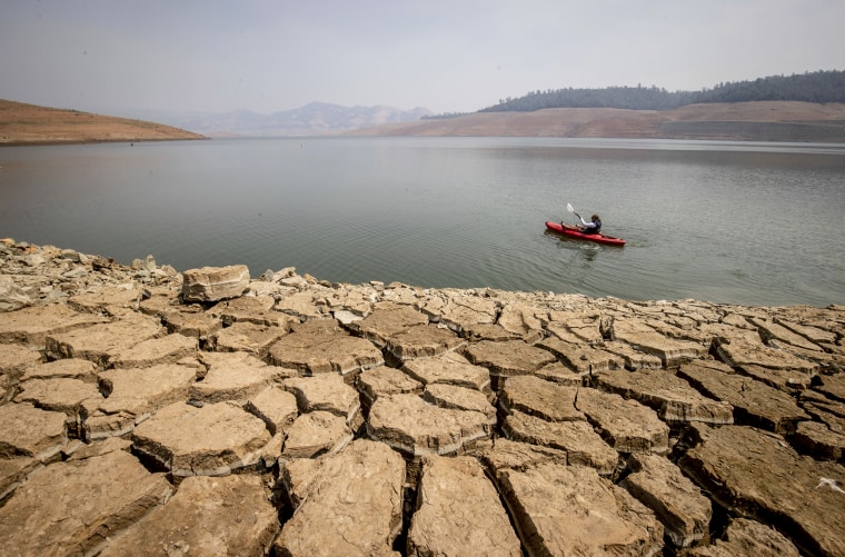 A kayaker fishes in Lake Oroville as water levels remain low due to continuing drought conditions in Oroville, Calif., on Aug. 22, 2021.