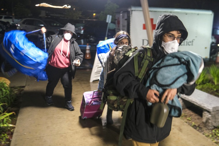People carrying their belongs arrive at an evacuation center in Santa Barbara, Calif., Monday, Jan. 9, 2023. (AP Photo/Ringo H.W. Chiu)