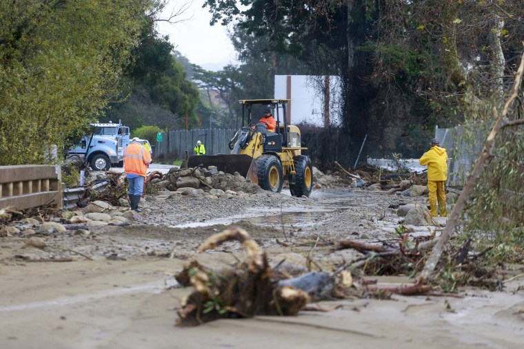 A work crew cleans up an area of Highway 101 that flooded in Montecito, Calif., Tuesday, Jan. 10, 2023. California saw little relief from drenching rains Tuesday as the latest in a relentless string of storms swamped roads, turned rivers into gushing flood zones and forced thousands of people to flee from towns with histories of deadly mudslides.