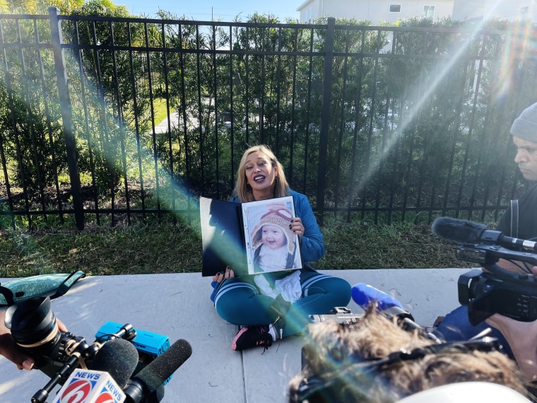Brazilian American Vanessa Viana holds a picture of her son when he was a baby outside the house where Brazil's former President Jair Bolsonaro is staying in Florida.