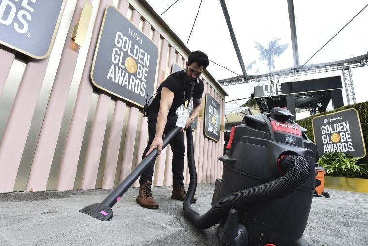 Event staff clear water from the carpet before the start of the 80th annual Golden Globe Awards at the Beverly Hilton Hotel on Tuesday, Jan. 10, 2023, in Beverly Hills, Calif.