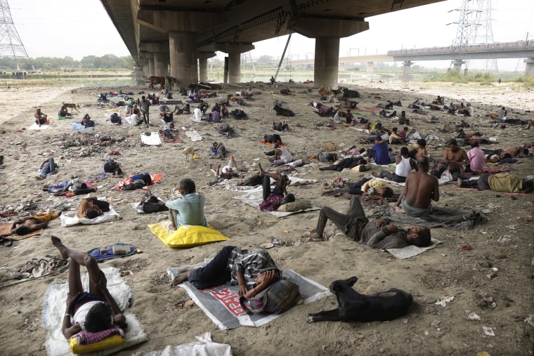 Homeless people sleep in the shade of a bridge during extreme heat conditions in New Delhi on May 20, 2022.