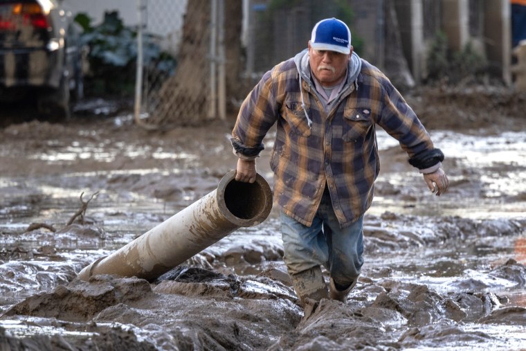 Residents work to push back wet mud that trapped cars and invaded some houses on January 11, 2023 in the small unincorporated town of Piru, east of Fillmore, California. A series of powerful storms continues to pound California in striking contrast to the past three years of severe to extreme drought experienced by most of the state. The storms are damaging yet bringing heavy rainfall totals which, though not expected to end the drought, is helping to refill reservoirs that have shrunken to historic low levels because of drought.