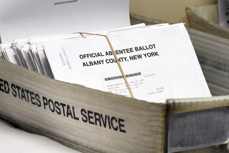 In this June 30, 2020, file photo, a box of absentee ballots wait to be counted at the Albany County Board of Elections in Albany, N.Y. Never before in U.S. history will so many people exercise the right on which their democracy hinges by marking a ballot at home and entrusting several layers of mostly unseen intermediaries to ensure their votes get accurately counted.