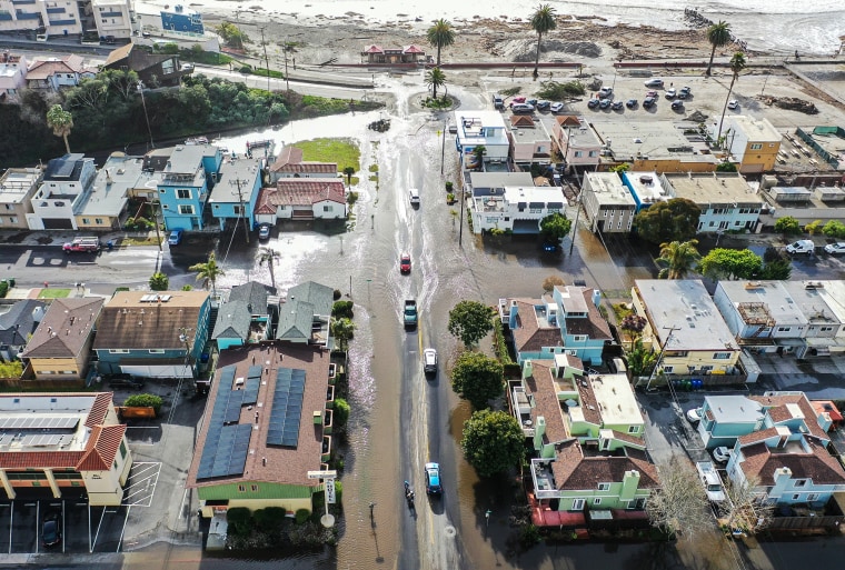 Image: vehicles drive along a flooded street close to the beach on Jan. 10, 2022 in Aptos, Calif.