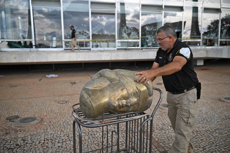A police officer carries away part of a vandalized sculpture at the Supreme Court building in Brasilia on Jan. 10, 2023. 