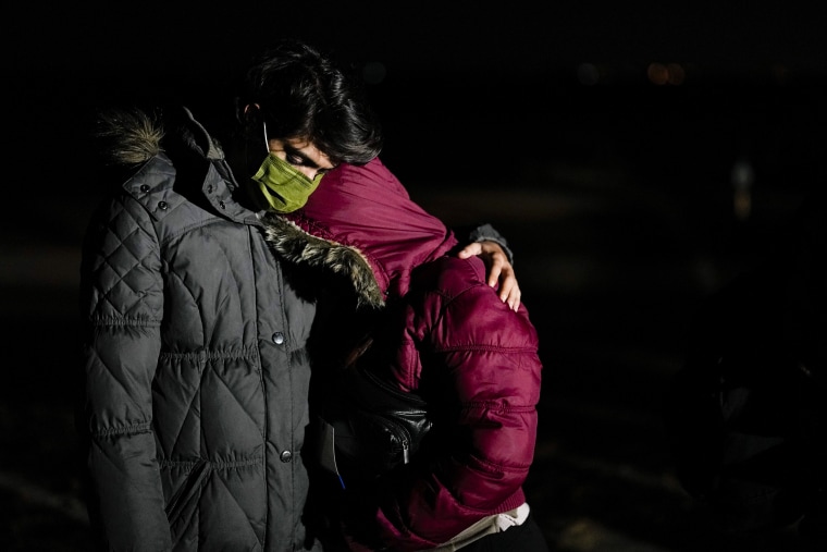 A Cuban migrant holds his wife as they wait to be processed to seek asylum after crossing the border into the United States on Jan. 6, 2023, near Yuma, Ariz.