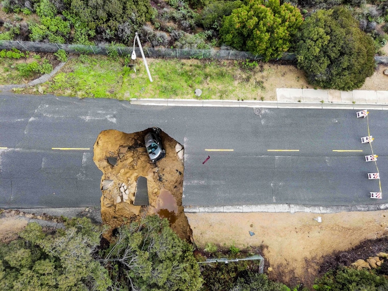 Image: Two cars parked in a large sinkhole that opened up during a day of unrelenting rain, on January 10, 2023, in the Chatsworth neighborhood of Los Angeles.