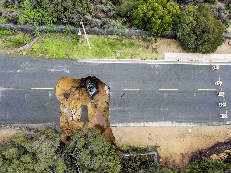 Imagen: Dos autos parados en un gran sumidero que se abrió en un día de lluvia incesante el 10 de enero de 2023 en el vecindario de Chatsworth en Los Ángeles.