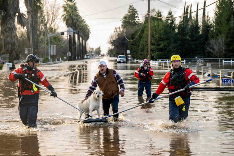 Image: San Diego firefighters help Humberto Maciel rescue his dog  from his flooded home in Merced, Calif., on Jan. 10, 2023.