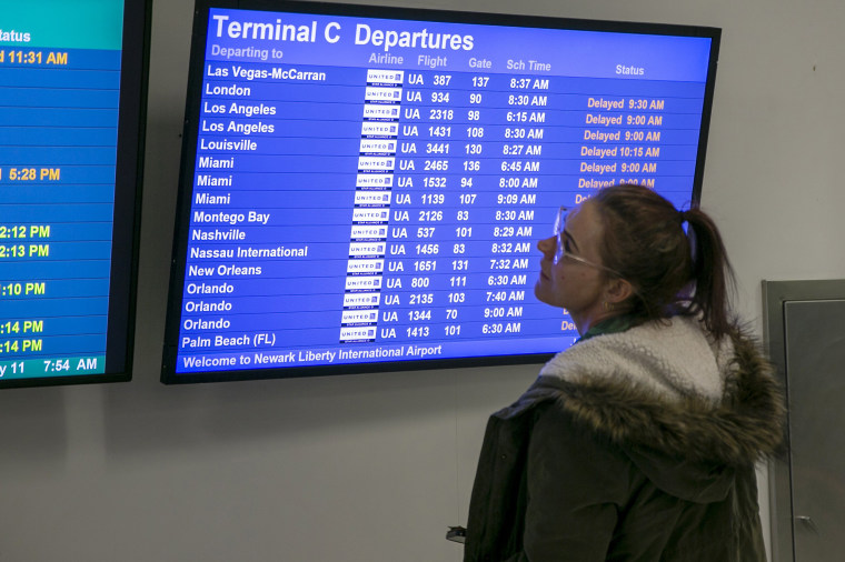A person checks the boards as flights are delayed and canceled at Newark Liberty International Airport