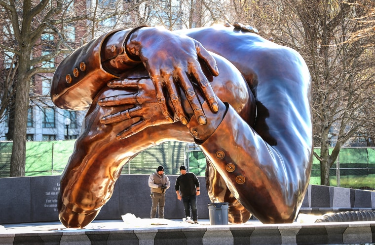 Workers stand beneath "The Embrace" sculpture in Boston Common, waiting for concrete to be poured, on Dec. 14, 2022.