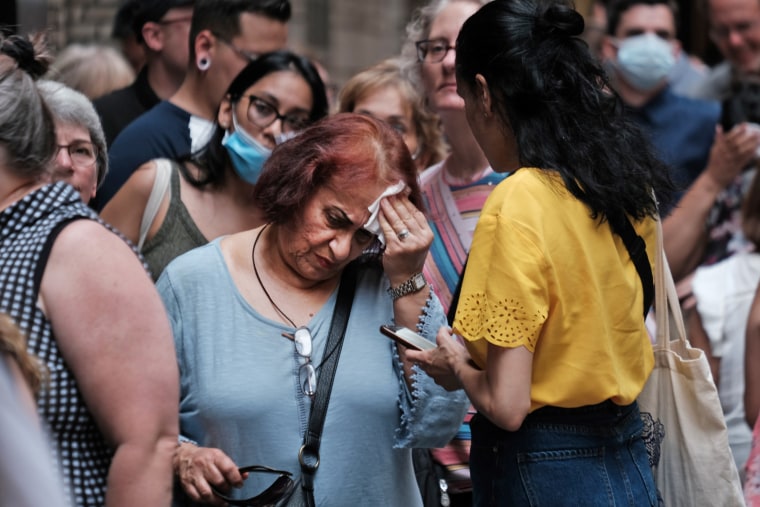 A woman wipes her brow as people wait in line in Midtown Manhattan during a heat wave on July 21, 2022.