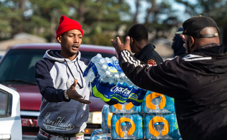 Dontavious Spann, left, with the Mississippi Rapid Response Coalition, and volunteer Preston Alston of Jackson, Miss., help to distribute water to Jackson, Miss., residents near Northside Drive and Manhattan Road on Dec. 27, 2022. 