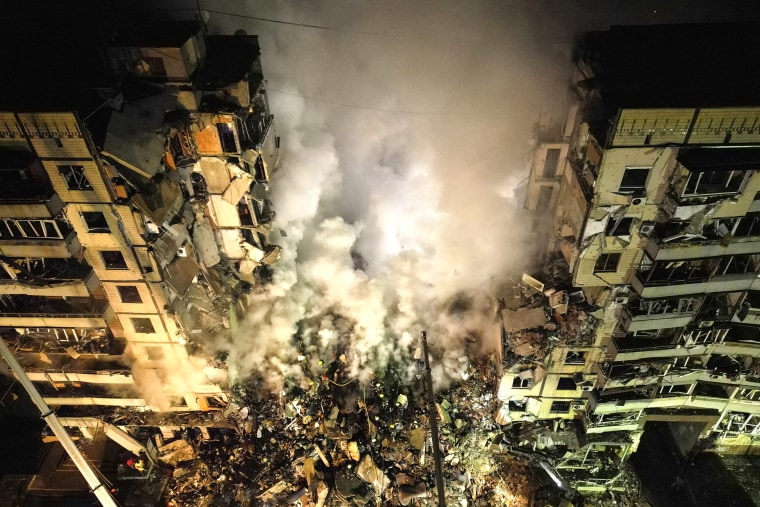 Emergency workers clear the rubble after a Russian rocket hit a multistory building leaving many people under debris in the southeastern city of Dnipro, Ukraine, on Jan. 14, 2023. 
