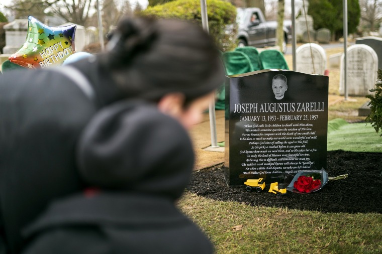 Elizabeth Fleisher talks with her son Sullivan, 6, by the newly unveiled gravestone for recently identified Joseph Augustus Zarelli at the Ivy Hill Cemetery in Philadelphia on Jan. 13, 2023.