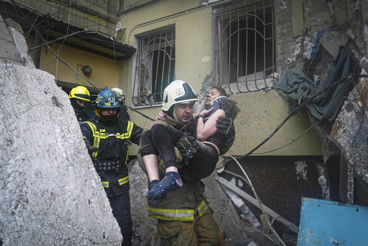 A firefighter carries a wounded woman out of the rubble after a Russian rocket attack on Saturday in Dnipro, Ukraine.
