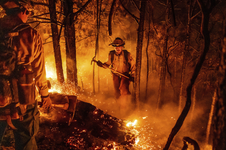 Firefighter Christian Mendoza manages a backfire, flames lit by firefighters to burn off vegetation, while battling the Mosquito Fire in Placer County, Calif., on Sept. 13, 2022.