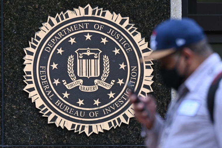 A pedestrian on their phone walks past J. Edgar Hoover FBI building