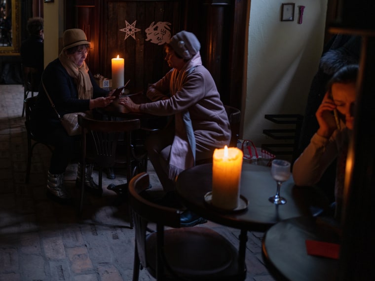 People sit in a dark cafe during a blackout following Russian strikes Dec. 29, 2022, in Lviv, Ukraine. 