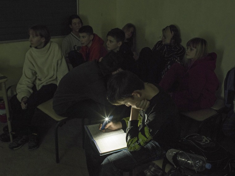 Image: A student uses light from a phone to study in a school's shelter, in Kyiv, Ukraine, Dec. 21