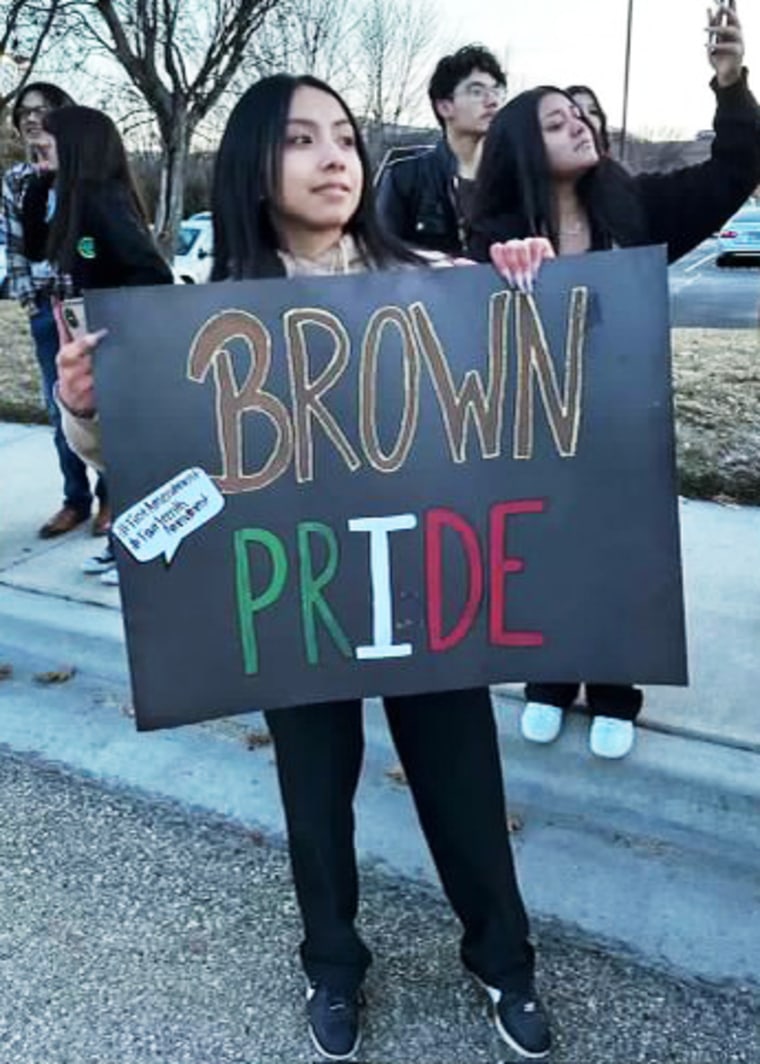 A participant in the protest organized by the students holding a "brown pride" poster.