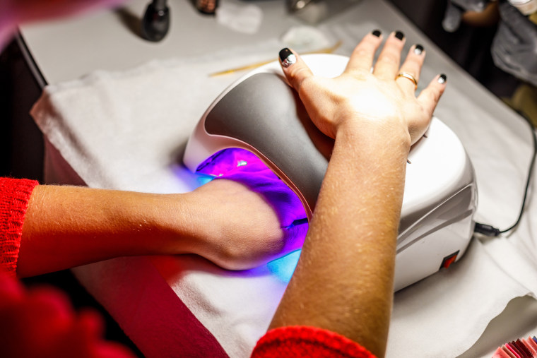 Woman's hand in a lamp for manicure. Dries nails after polishing.