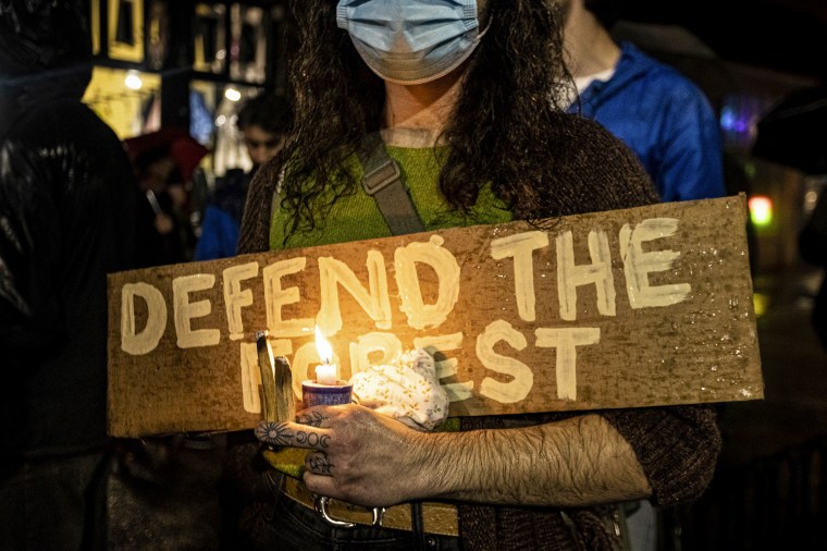 A protester holds up a sign that says "Defend the Forest" during a candlelight vigil for an eco-activist who was shot and killed in an incident near the site of a proposed Atlanta law enforcement training center on Jan. 18, 2023, in Atlanta.