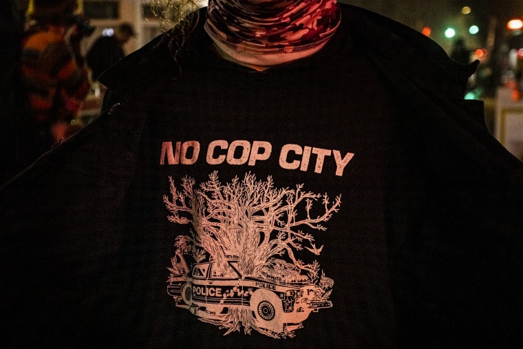 A protester wears a shirt that says "No Cop City" during a candlelight vigil for an eco-activist who was shot and killed near the site of a proposed Atlanta law enforcement training center on Jan. 18, 2023, in Atlanta.