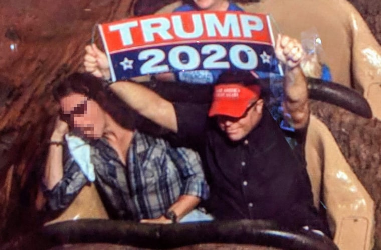 Dion Cini holds a Trump 2020 banner at Walt Disney World. Image blurred by source.