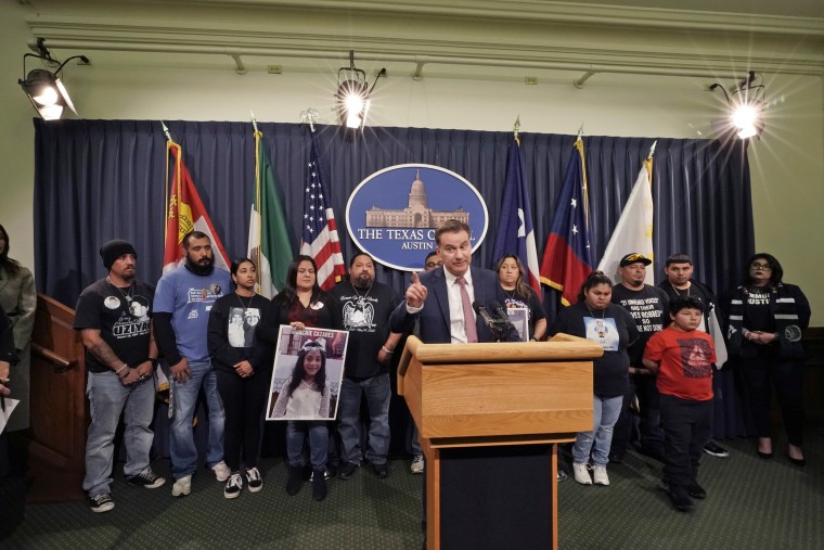 Family members of those killed by a gunman at Robb Elementary School in Uvalde, Texas, stand with Texas State Sen. Roland Gutierrez, during a news conference at the Texas Capitol on Jan. 24, 2023. 
