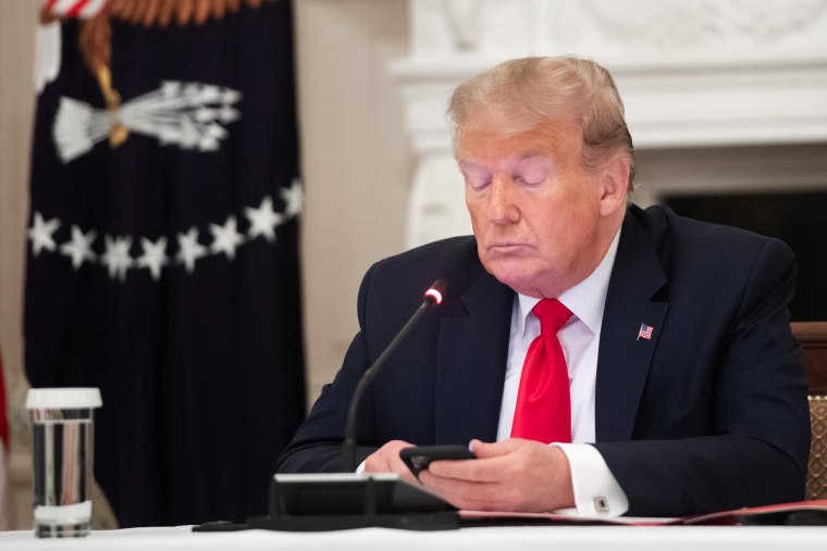 President Donald Trump uses his cellphone in the State Dining Room of the White House in Washington, D.C.