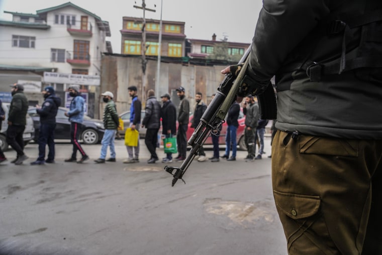 An Indian policeman guards a line of Kashmiri men during a surprise security check in Srinagar on Jan. 9, 2023. 