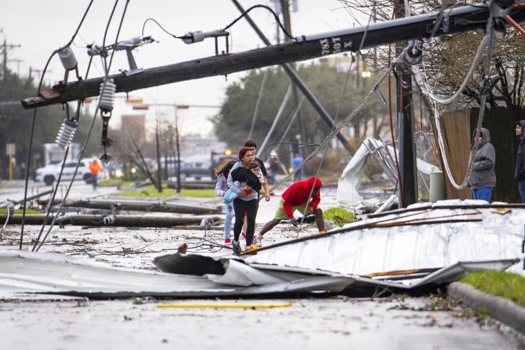 People cross under downed power lines after a tornado passed through Pasadena, Texas 