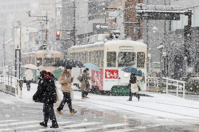 People cross the street as it snows in Toyama, Japan, on Jan. 24, 2023.