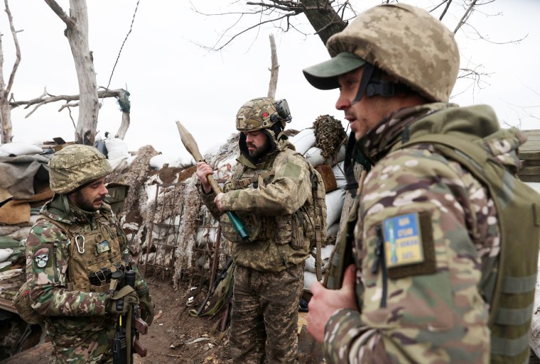 Ukrainian servicemen examine an RPG rocket in a trench in Donetsk, Ukraine 