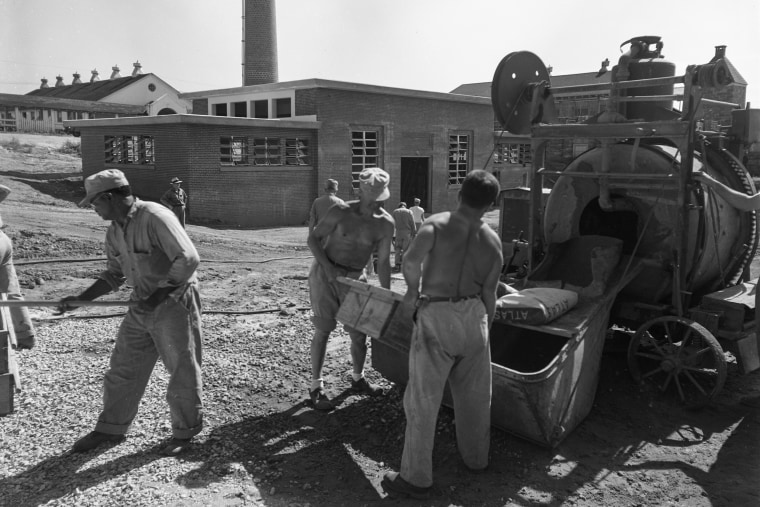 Incarcerated persons work with farm equipment at the Atlanta Prison Farm in December 1953.