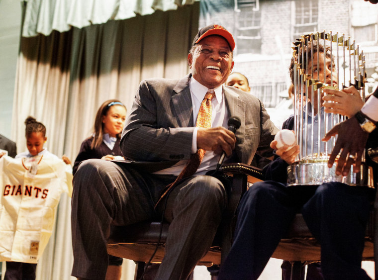 Willie Mays smiles while a student from P.S. 46 with the Major League Baseball World Series trophy in Harlem, New York on January 21, 2011.