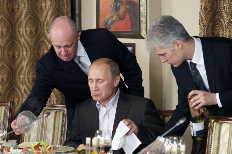Wagner chief Yevgeny Prigozhin, left, serves food to Russian Prime Minister Vladimir Putin at his restaurant outside Moscow in 2011. 